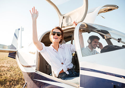 Jeune femme dans un petit avion de loisir saluant le photographe